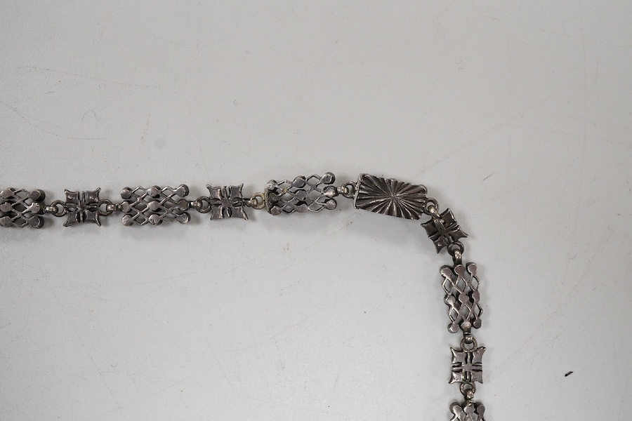 An early 20th century white metal and white paste set cluster necklace, each trellis style link mounted with nine paste stones, approx. 38cm.